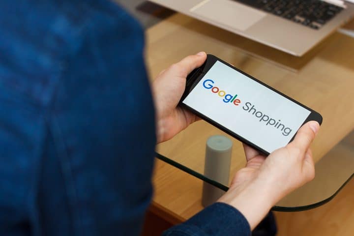 Kvinna håller i mobiltelefon med Google Shopping på